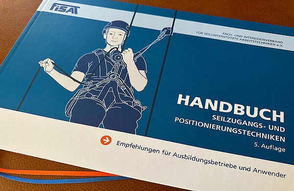 Cover FISAT Handbuch Seilzugangs‑ und Positionierungstechniken (5. Auflage) mit Kletterer‑Illustration und Ausbilder‑Empfehlungen.